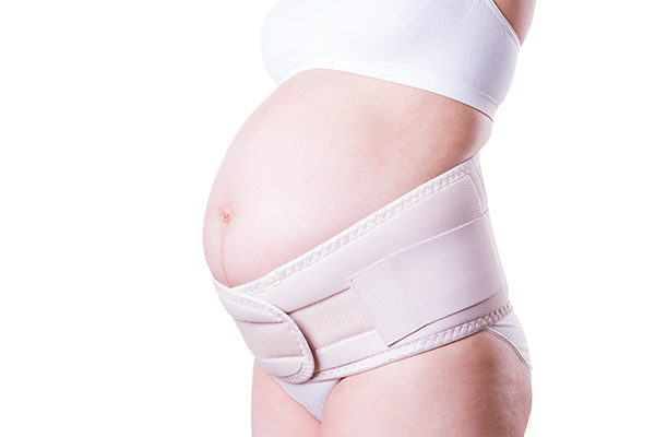 side profile of pregnant belly supported by a maternity belt